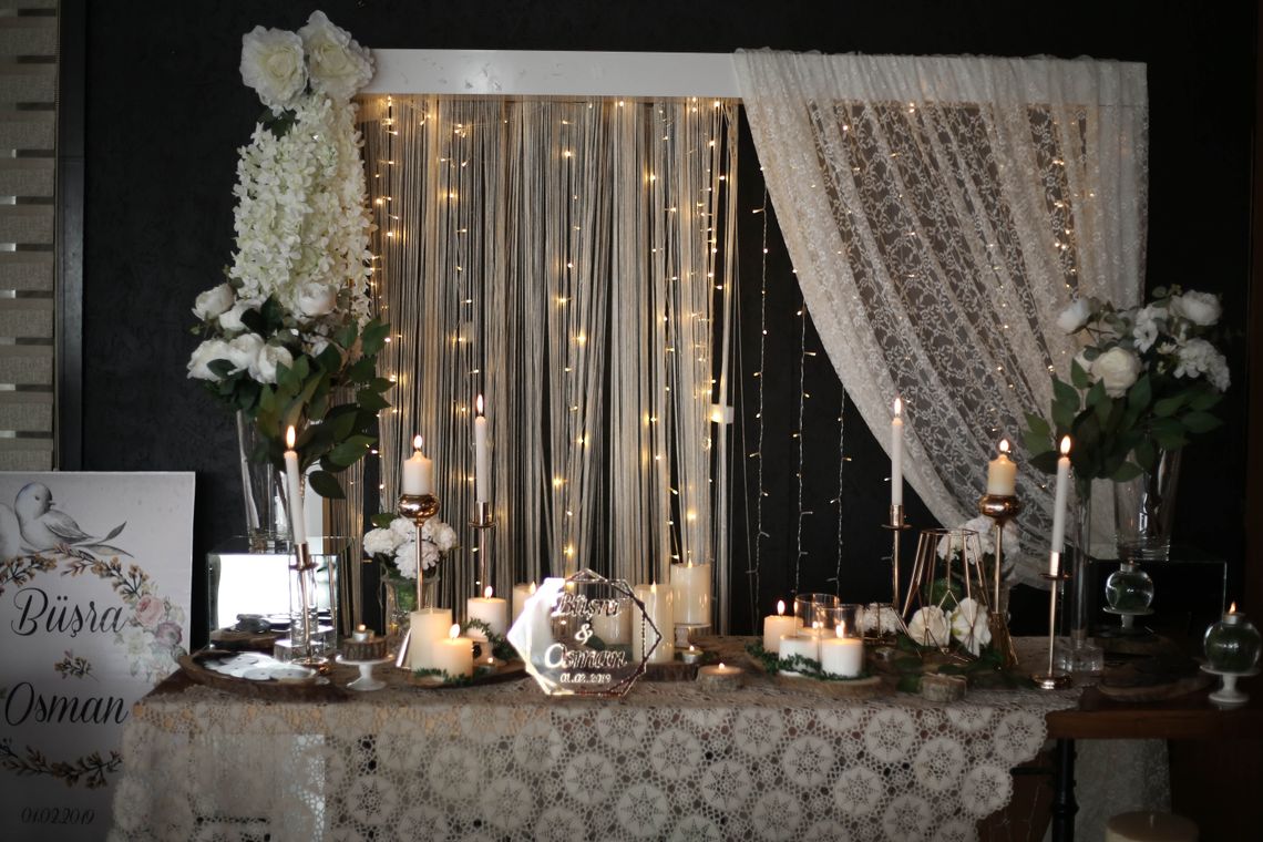 Romantic celebration table styled with candles, flowers, lace, and warm event lighting