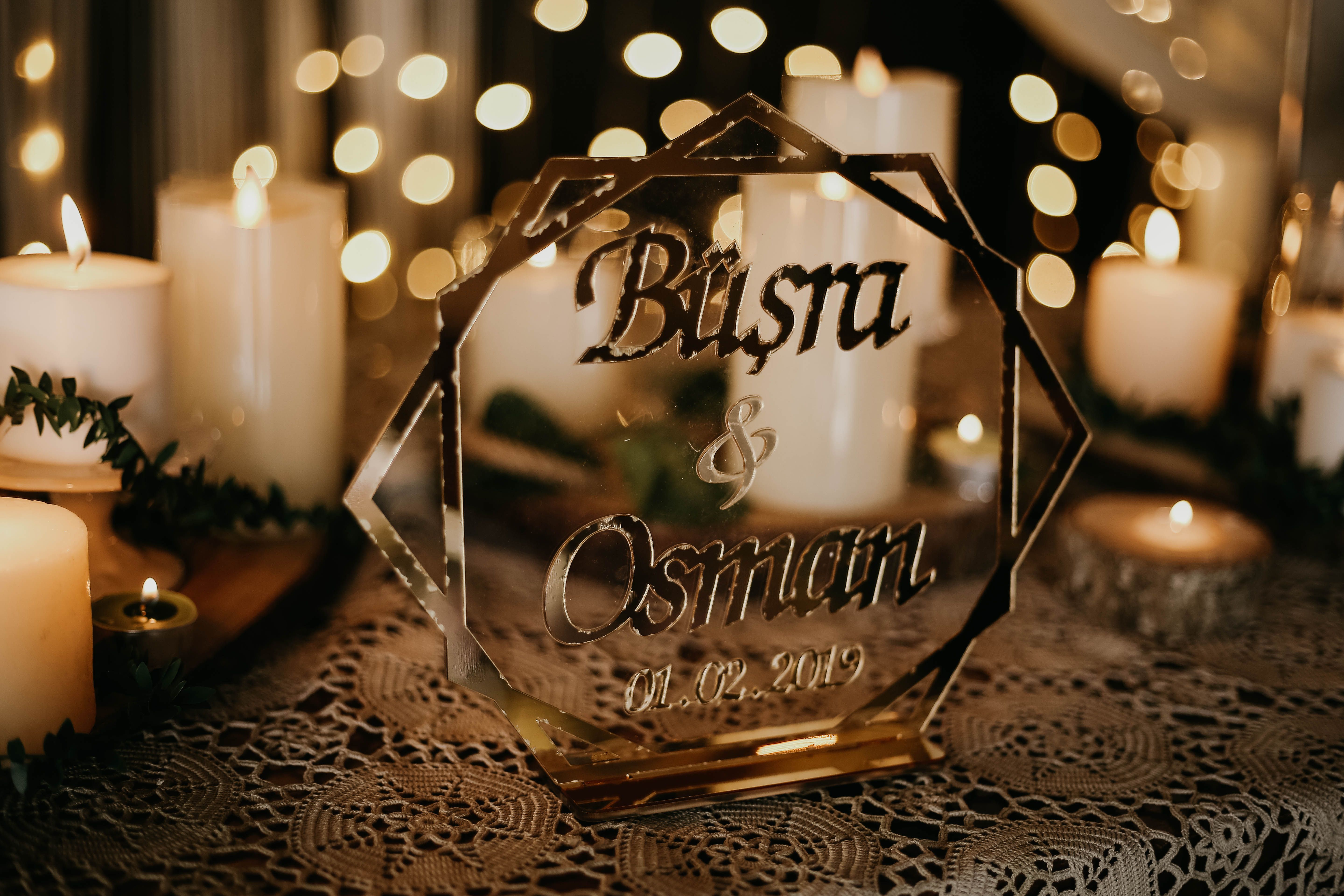 A romantic wedding table setting with candles and a personalized glass plaque.