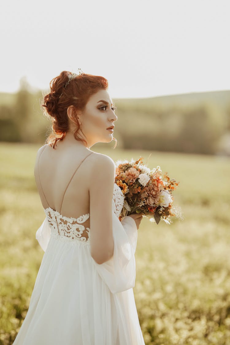 Redhead Woman With Tied Hair In White Lacy Dress In Flowery Meadow