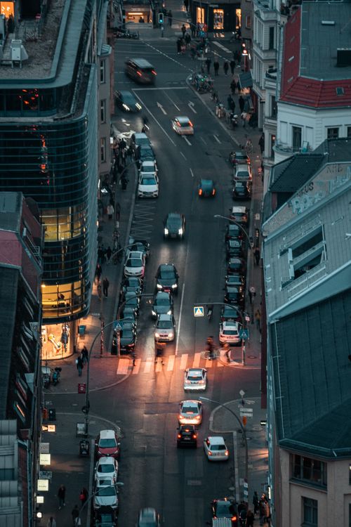 Free An aerial shot capturing a bustling city street with cars and pedestrians at a vibrant intersection during dusk. Stock Photo