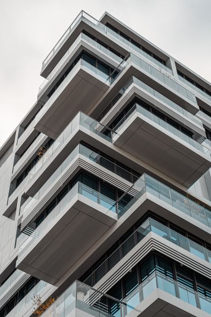 Contemporary urban apartment building featuring glass balconies and geometric design.