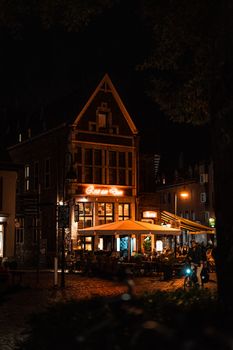 Cozy outdoor dining at a European restaurant, illuminated warmly at night.
