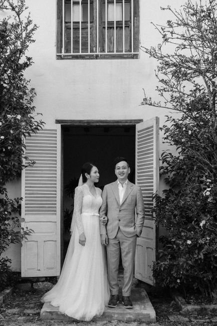 Charming black and white photo of a Vietnamese couple at a house entrance.