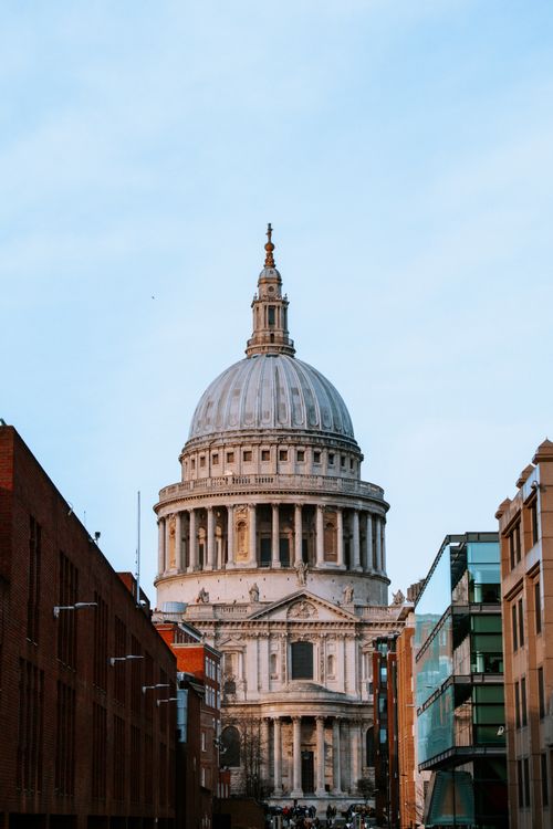 Free Iconic view of St. Paul's Cathedral in London framed by surrounding buildings on a clear day. Stock Photo