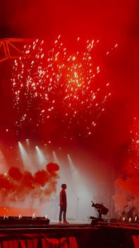 A performer captivates the audience during an electrifying night concert in London with stunning fireworks display.