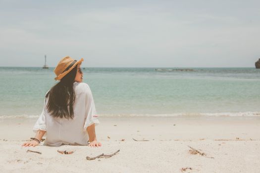 戴着草帽的女人在海滩上享受海浪中的宁静