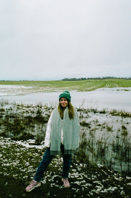 Free A woman in winter attire stands in a snowy rural field with puddles. Stock Photo