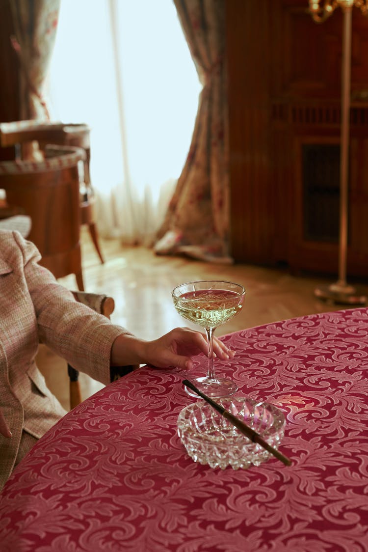 Female Hand Reaching To The Glass Of White Wine