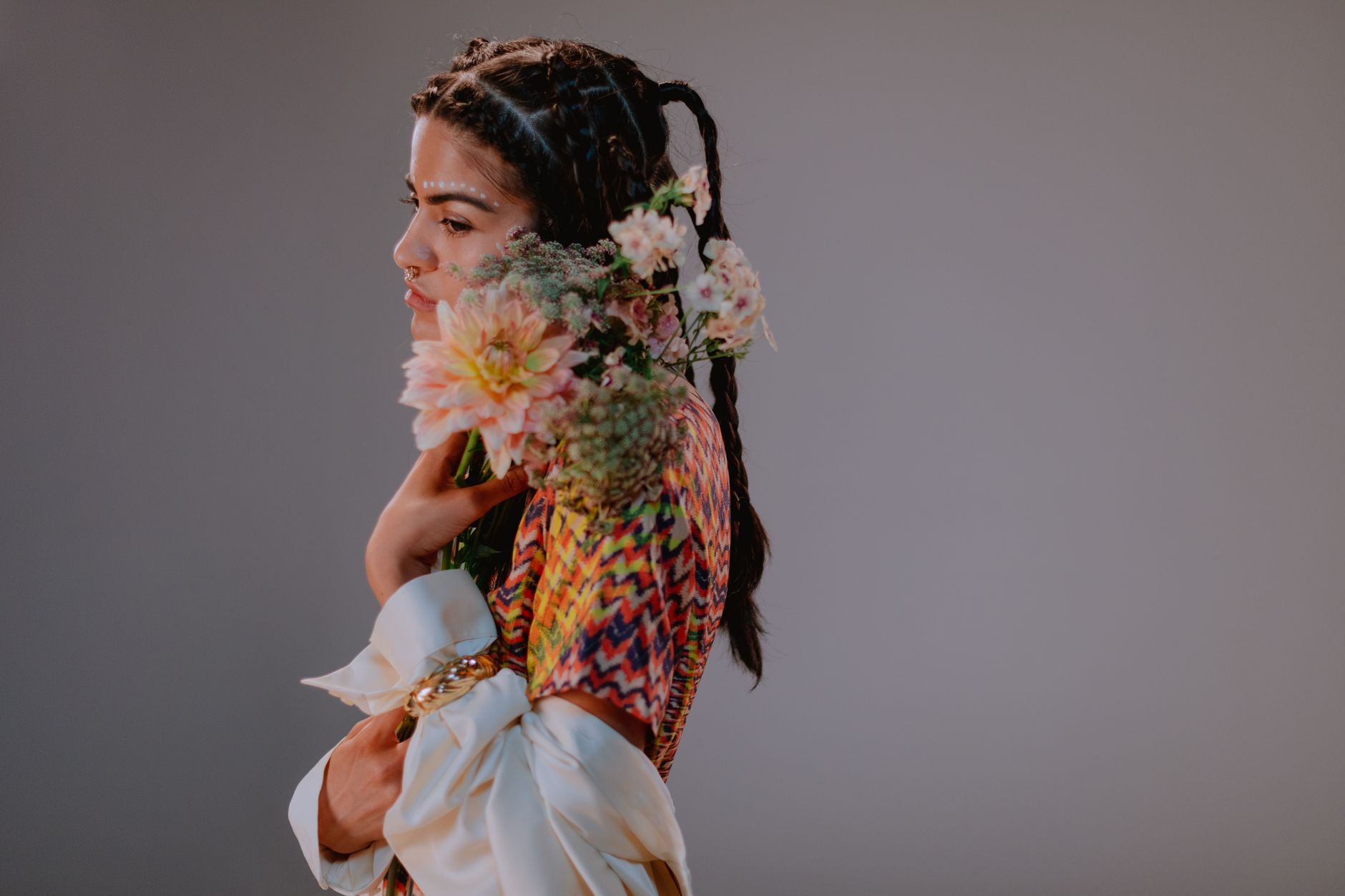 Side view of a woman in traditional attire, holding a bouquet, showcasing elegance and cultural beauty.