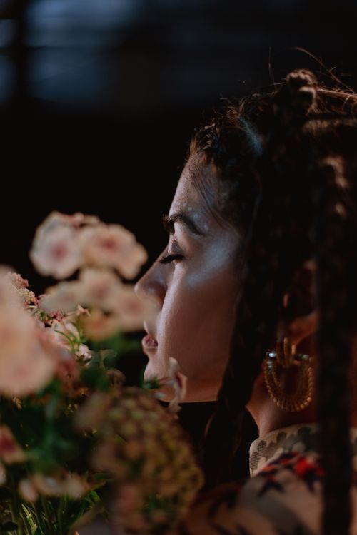 Free Profile view of a woman with braided hair smelling a bouquet of flowers. Stock Photo