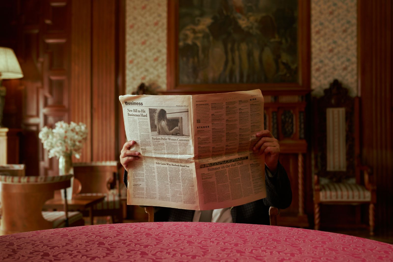 A person reading a folded newspaper