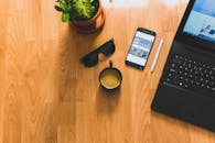 舒适的家庭办公室配备了笔记本电脑、咖啡杯、智能手机和盆栽植物，这样的环境非常适合提高工作效率