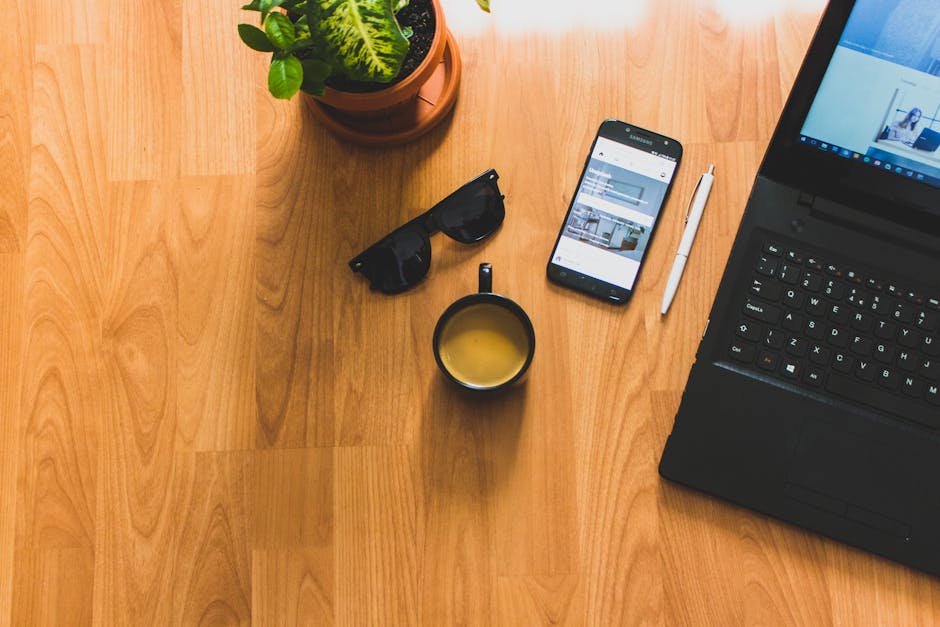 Does Monarch Actually Replace Mint in 2026? A cozy home office setup featuring a laptop, coffee mug, smartphone, and potted plant, perfect for productivity.
