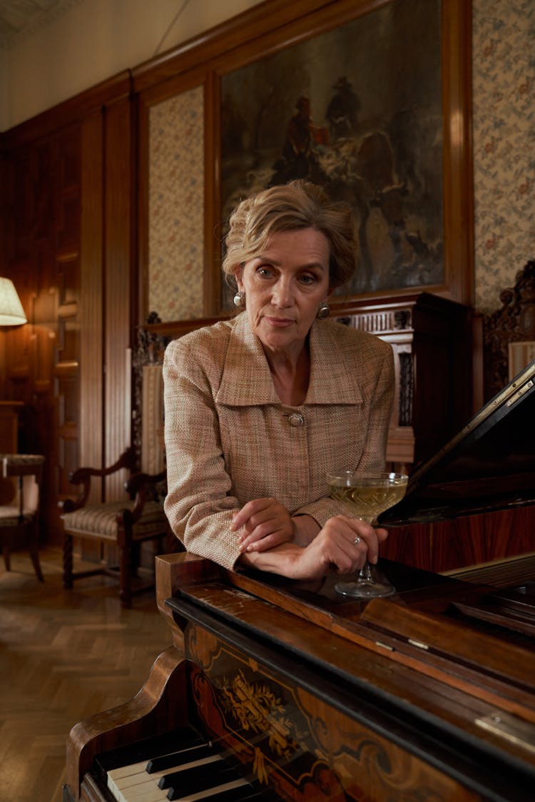 Elderly Woman Sitting By Piano In Luxury Room