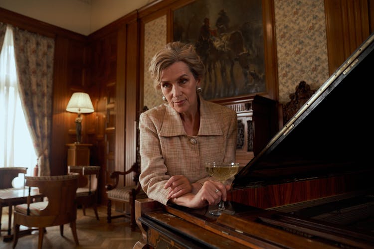 Elderly Woman Sitting By Piano In Luxury Room