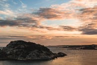 日落时分，美丽的夕阳洒在岩石岛屿上，云层翻涌，海面平静