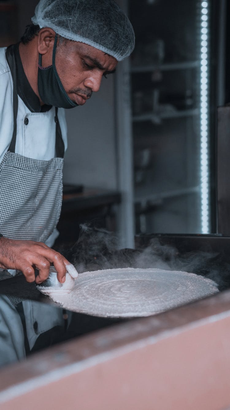 Man Frying Dough On Pan