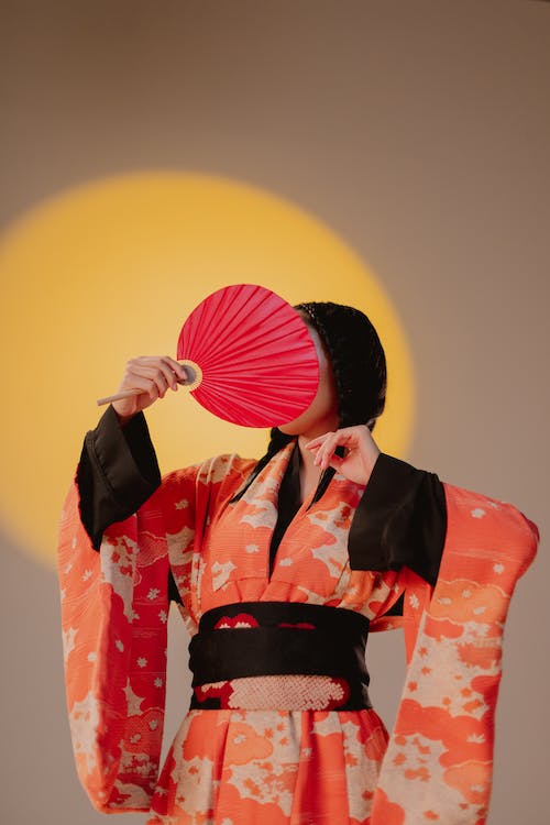 Free Woman Wearing Kimono Covering Face With a Fan Stock Photo