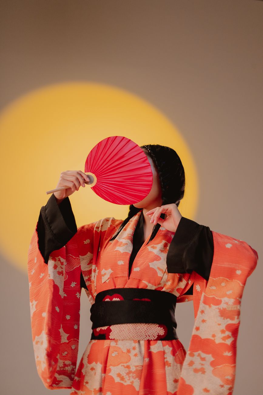 Artistic portrait of a woman in a vibrant kimono holding a fan, embodying Japanese elegance.