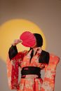 Woman Wearing Kimono Covering Face With a Fan