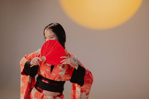 A Woman in Red Kimono Holding a Red Hand Fan