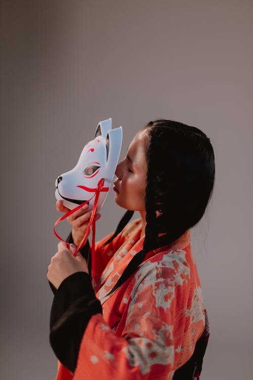 Free Woman Wearing a Kimono Holding an Animal Mask on Face Stock Photo
