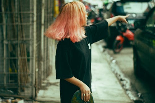 Woman Standing on the Sidewalk and Pointing 