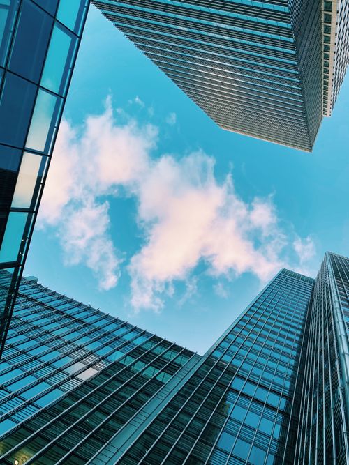 Free Low-angle shot of modern skyscrapers in London against a bright blue sky with clouds. Stock Photo