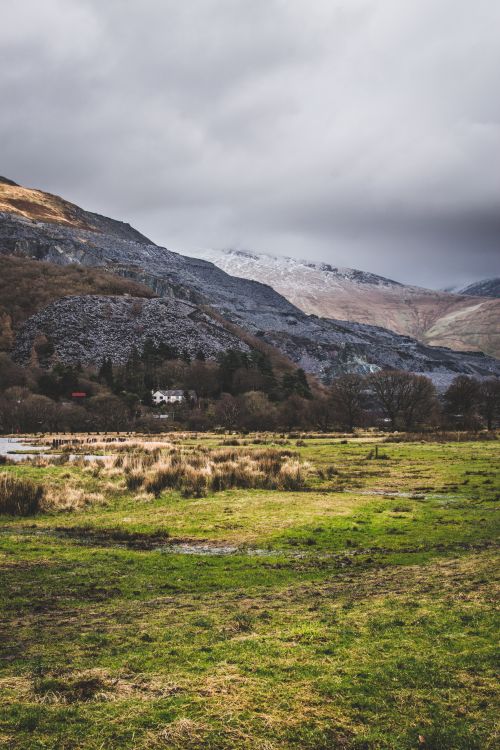 Free Stunning view of Llanberis countryside with grassy fields and mountains under cloudy skies. Stock Photo