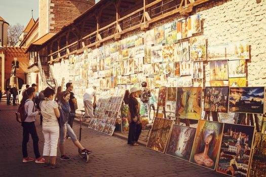 Street art gallery with people browsing vibrant paintings in daylight.