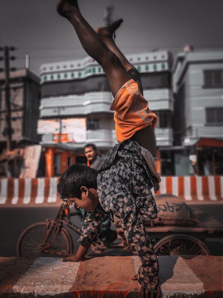 A Boy Wearing Long Sleeves And Orange Shorts Doing Hand Stand