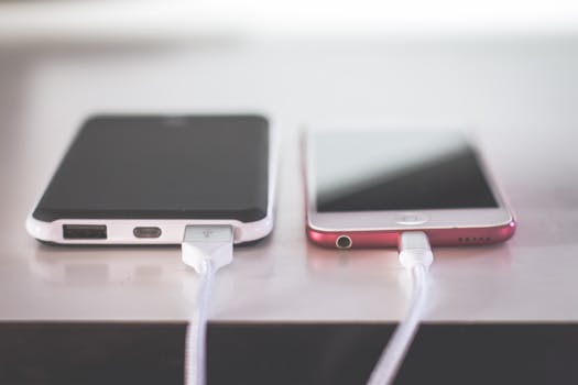 Two smartphones charging side by side on a desk. Modern and technological setting. by Steve Johnson