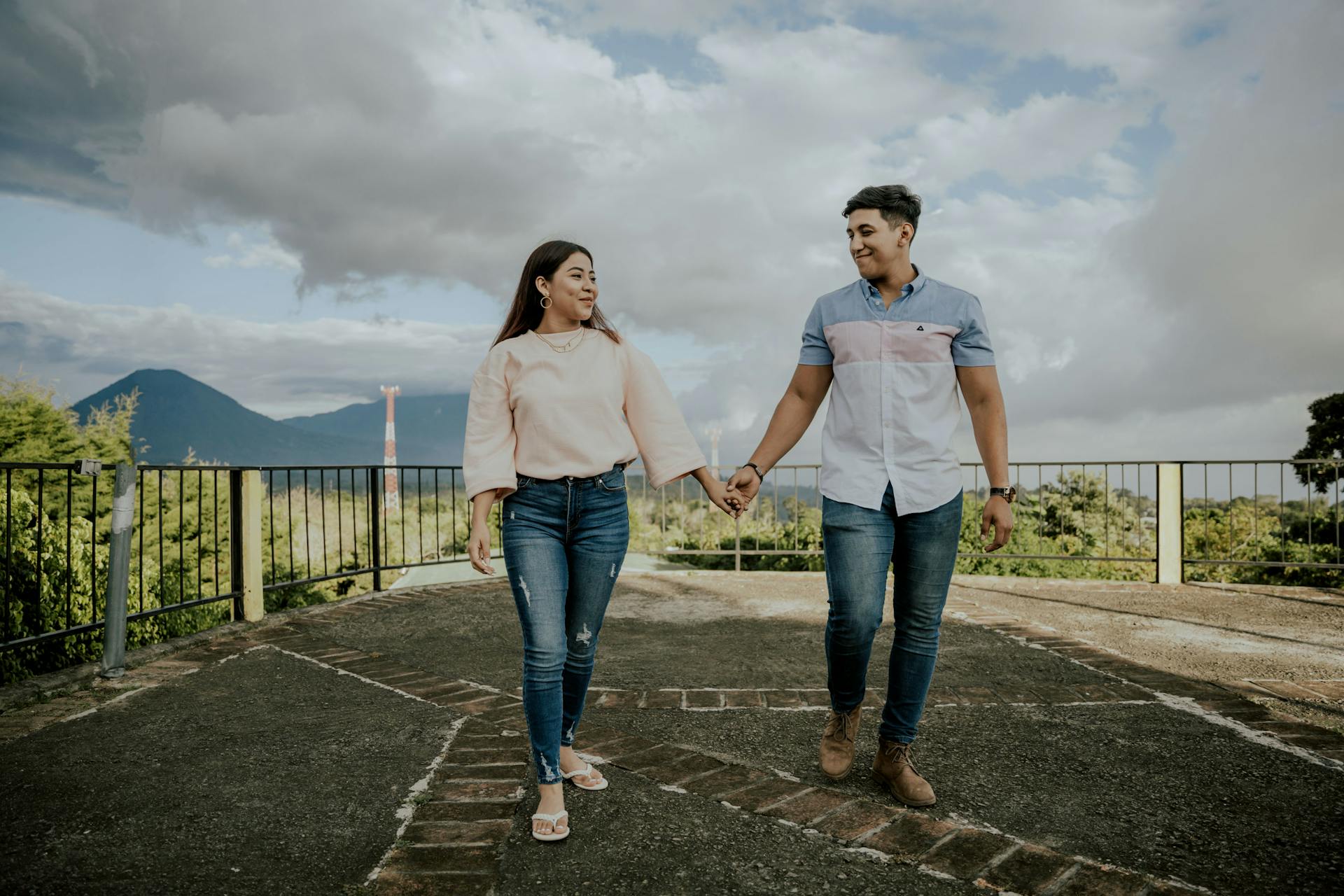 A couple enjoys a scenic walk holding hands in Salcoatitán, El Salvador with mountains in the background.