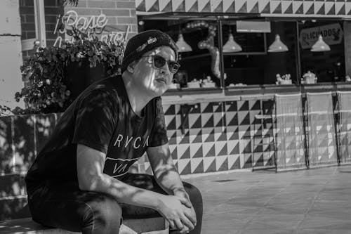 Man Wearing Beanie and Sunglasses Sitting on Concrete Bench