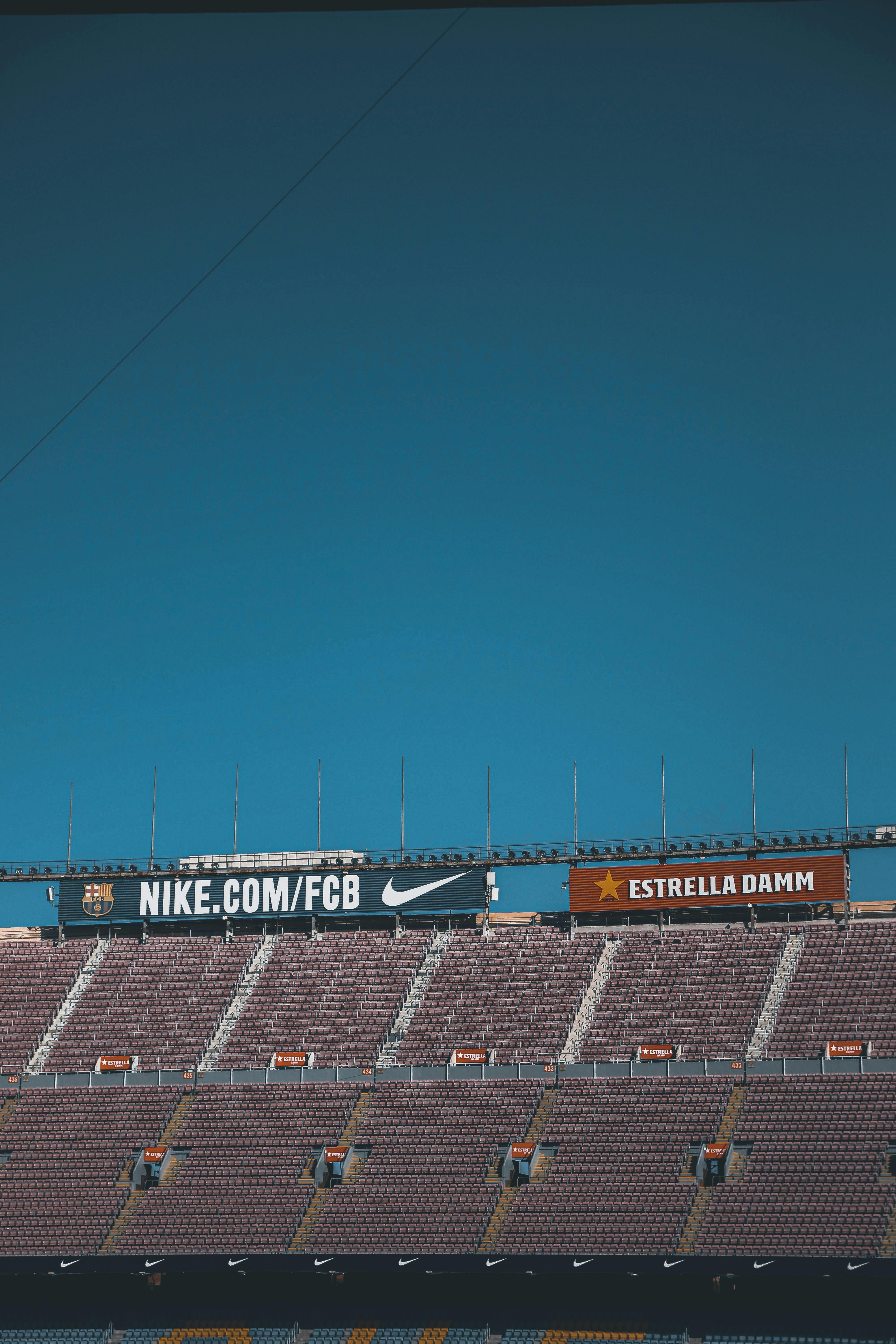 Free An empty stadium grandstand under a clear blue sky with visible signage, perfect for sports and event themes. Stock Photo