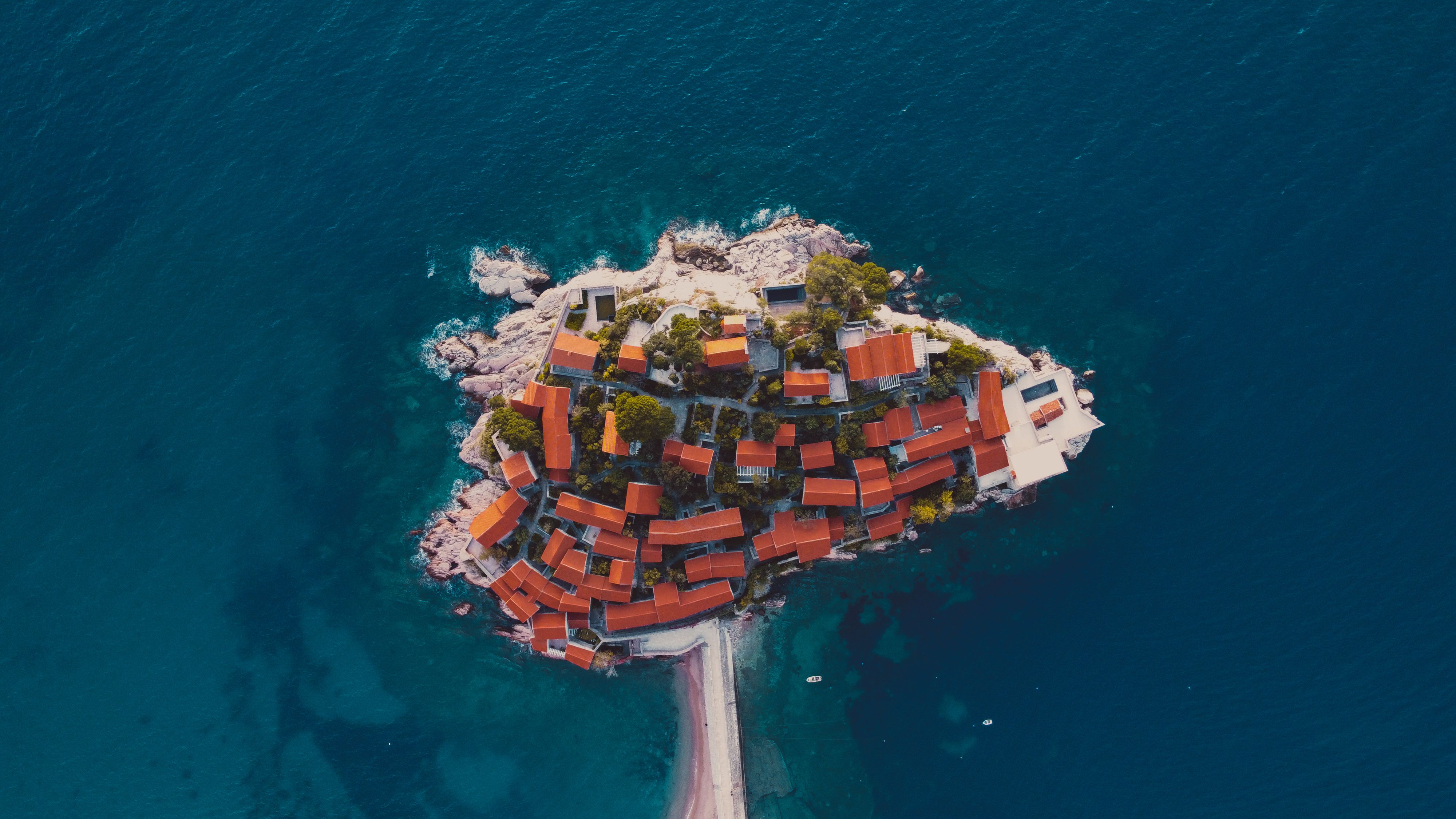 Aerial shot of a small island with red-roofed buildings surrounded by the sea.