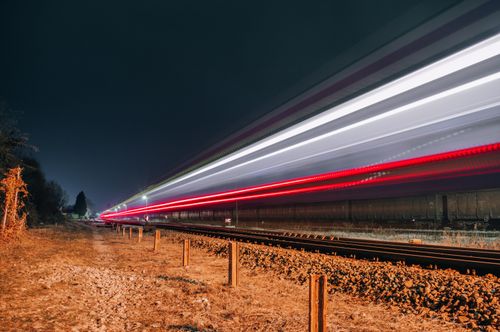 Free Long exposure of a train creating vivid light trails on a nighttime railway track. Stock Photo