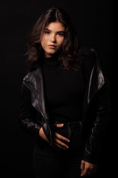 Elegant portrait of a woman wearing a black leather jacket in a studio setting.