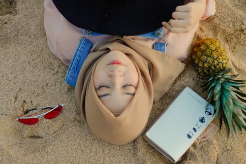 無料 サングラスの横にある砂の上に横たわる女性 写真素材
