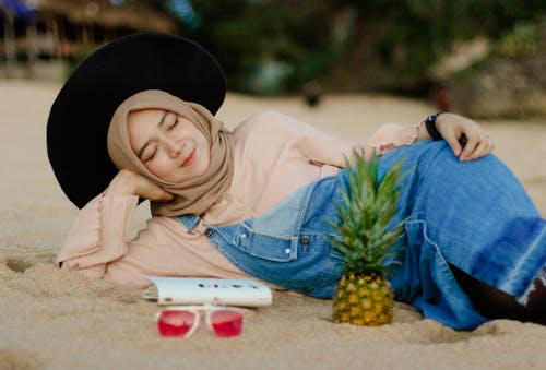 Woman in Blue Denim Dungaree Lying on Sand 
