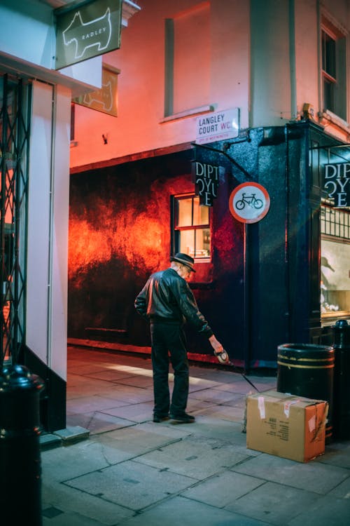 Free Man Dragging Cardboard Box through Street Stock Photo