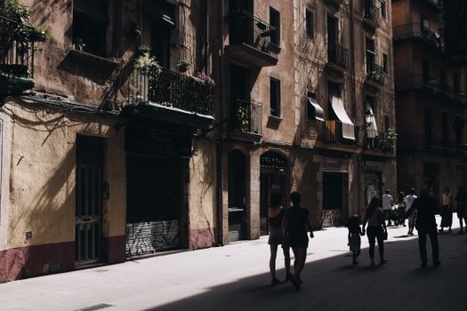 A bustling urban street in Barcelona with historical architecture and shadow play on the facades.