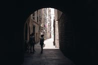 拱门下有一条阴暗的小巷，巷中有两个人影和一辆自行车