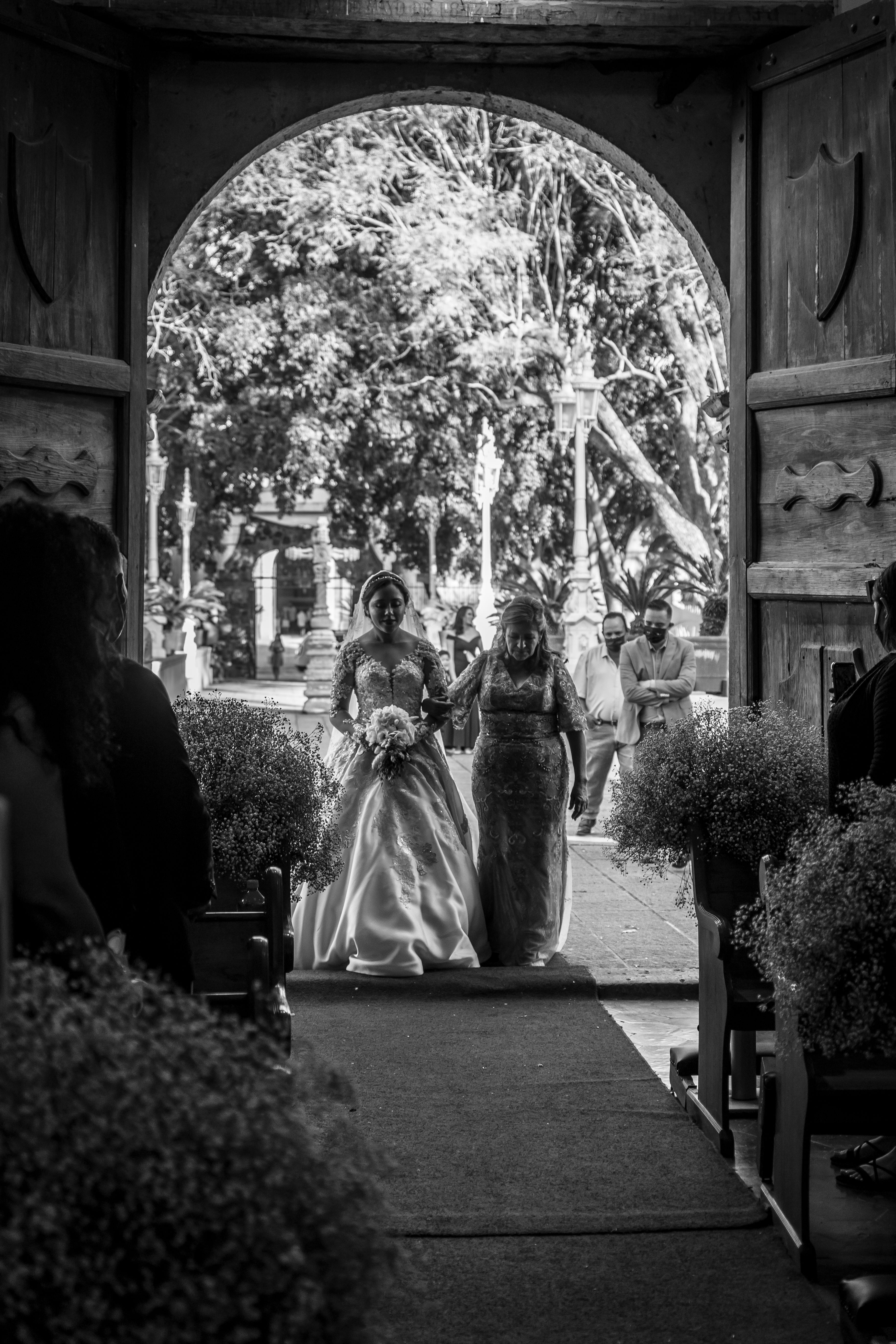 Bride and mother walking down the aisle at a wedding in black and white.