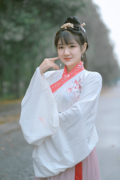Free A smiling woman in traditional Asian attire poses outdoors with a blurred background. Stock Photo