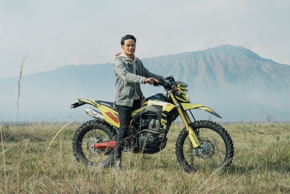 A man on a yellow dirt bike amidst East Java A man on a yellow dirt bike amidst East Java's scenic mountains, exuding adventure.