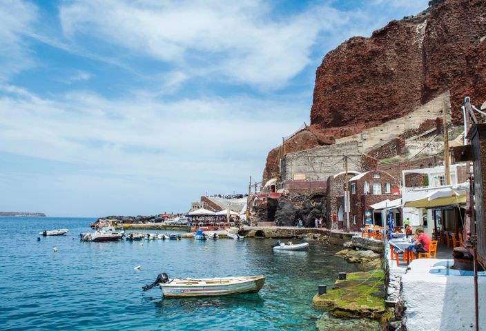 Picturesque view of Santorini's harbor with boats and iconic architecture.