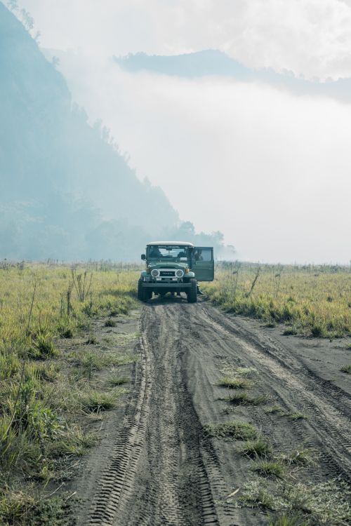 Free Explore the rugged beauty of East Java's countryside with a jeep in a foggy, picturesque setting. Stock Photo