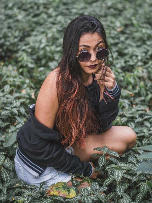 Free Woman in Black Jacket Sitting Beside Green Plants Stock Photo