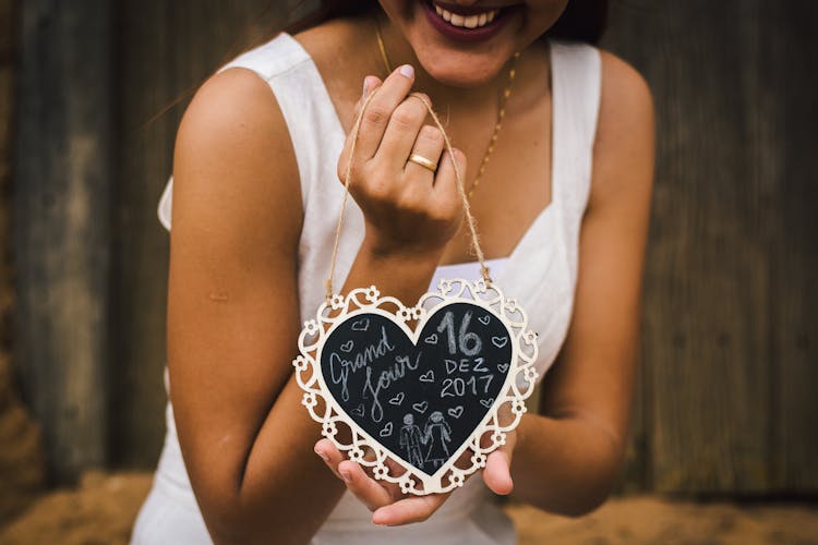 Woman Holding A Heart Shaped Board And Smiling 